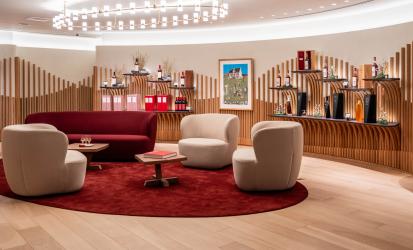Interior image of a lounge-style boutique with red carpet, wood walls and a selection of bottles of The Macallan around the walls