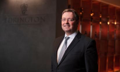 Edrington CEO Scott McCroskie standing in front of the Edrington sign at the Glasgow headquarters