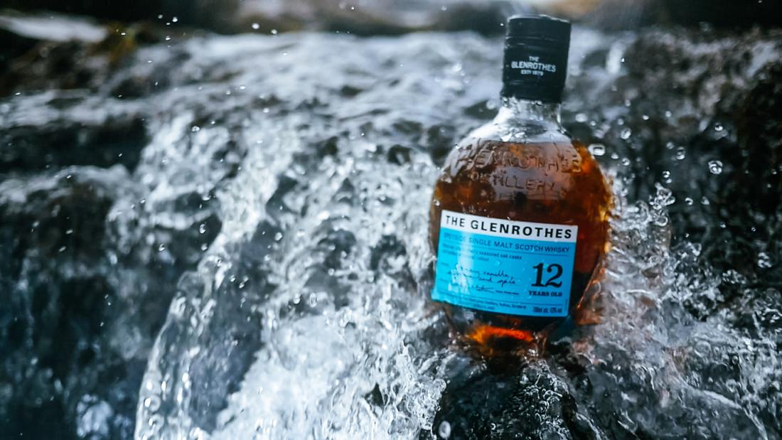 The Glenrothes Aqua 12 Year Old bottle in front of a waterfall
