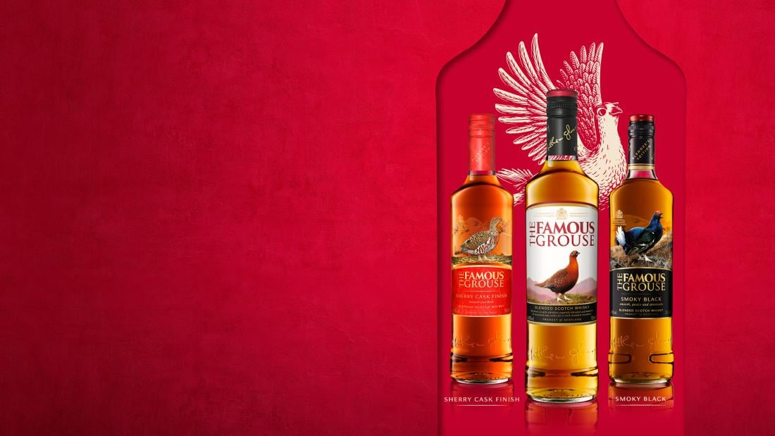 Bottles of The Famous Grouse Blended Scotch Whisky against a red background