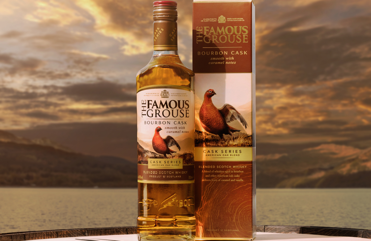 Close up of The Famous Grouse Bourbon Cask bottle and pack in front of a mountain landscape