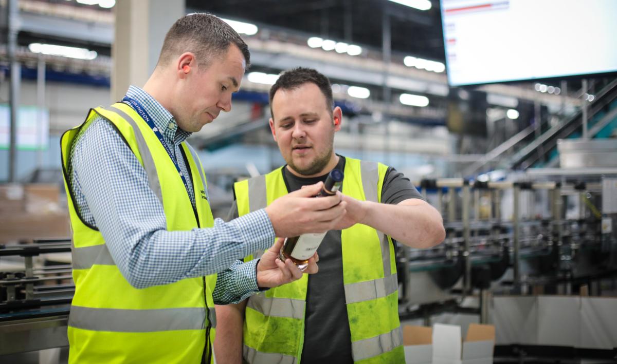 Two colleagues looking at a bottle on the bottling line