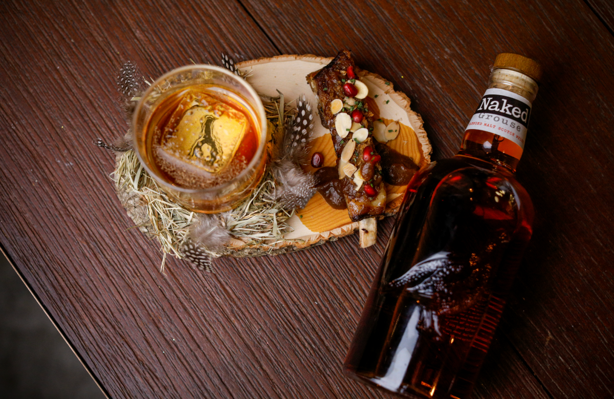 Bottle of Naked Grouse lying next to a dram glass