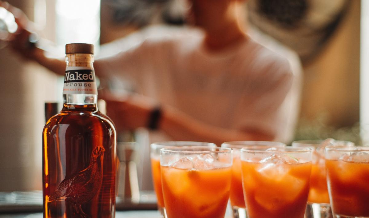 A bottle of Naked Grouse next to four cocktails