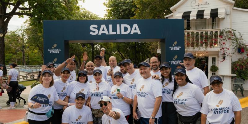 A group shot of colleagues in the Dominican Republic in front of a Casa Brugal stride sign