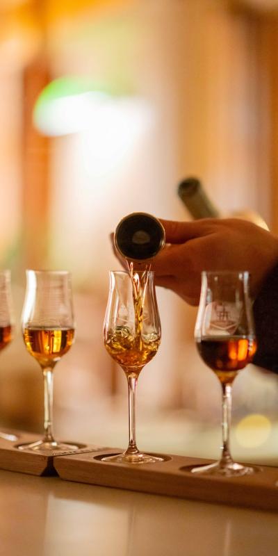 A hand pouring a measure of whisky from a jigger