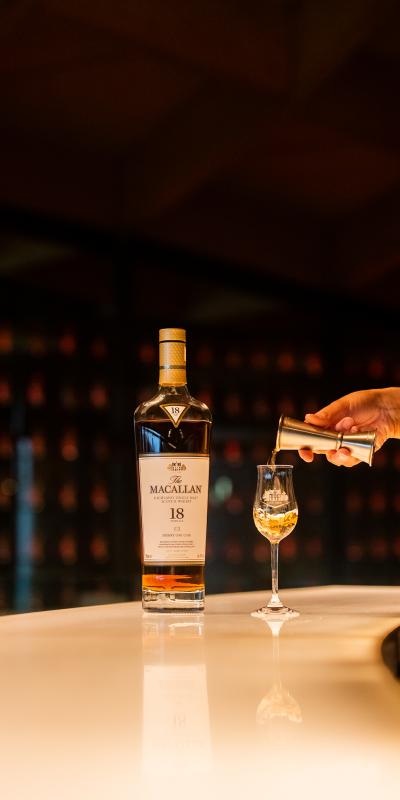 A measure of The Macallan is poured into a tasting glass, next to a bottle of The Macallan