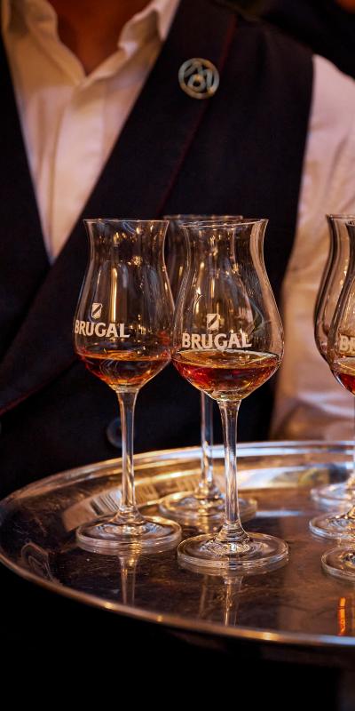 A man holding a silver tray with branded Brugal long tulip glasses
